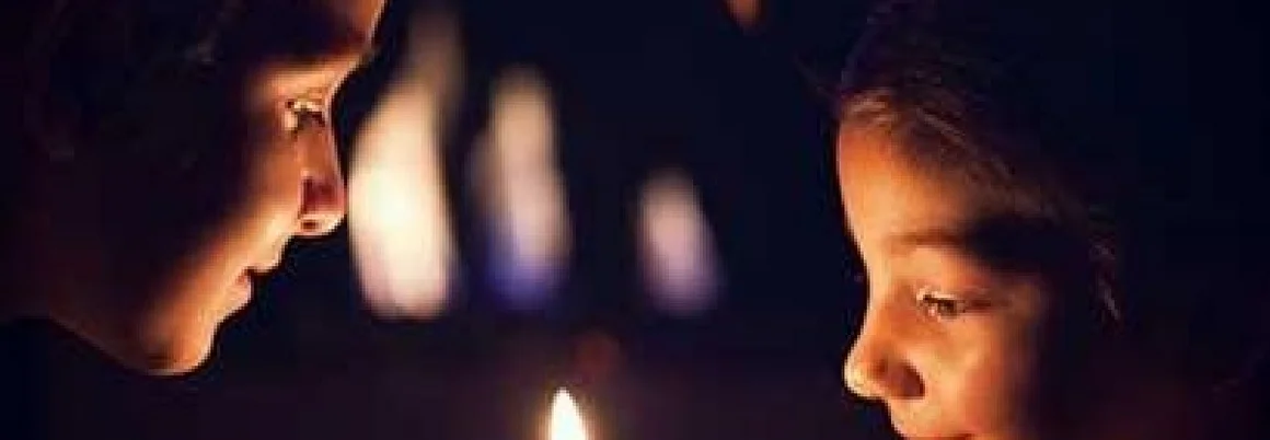 Zwei Kinder betrachten Kerze